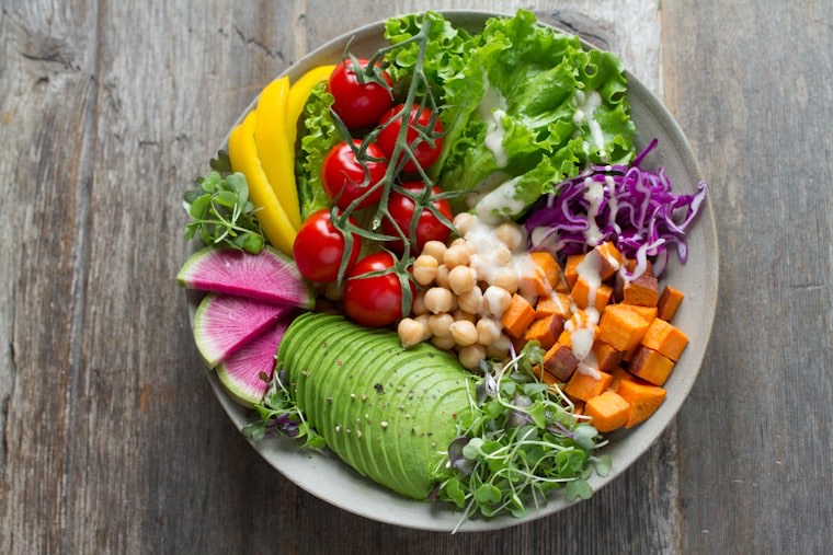 A colourful bowl of chickpeas, roasted vegetables and greens
